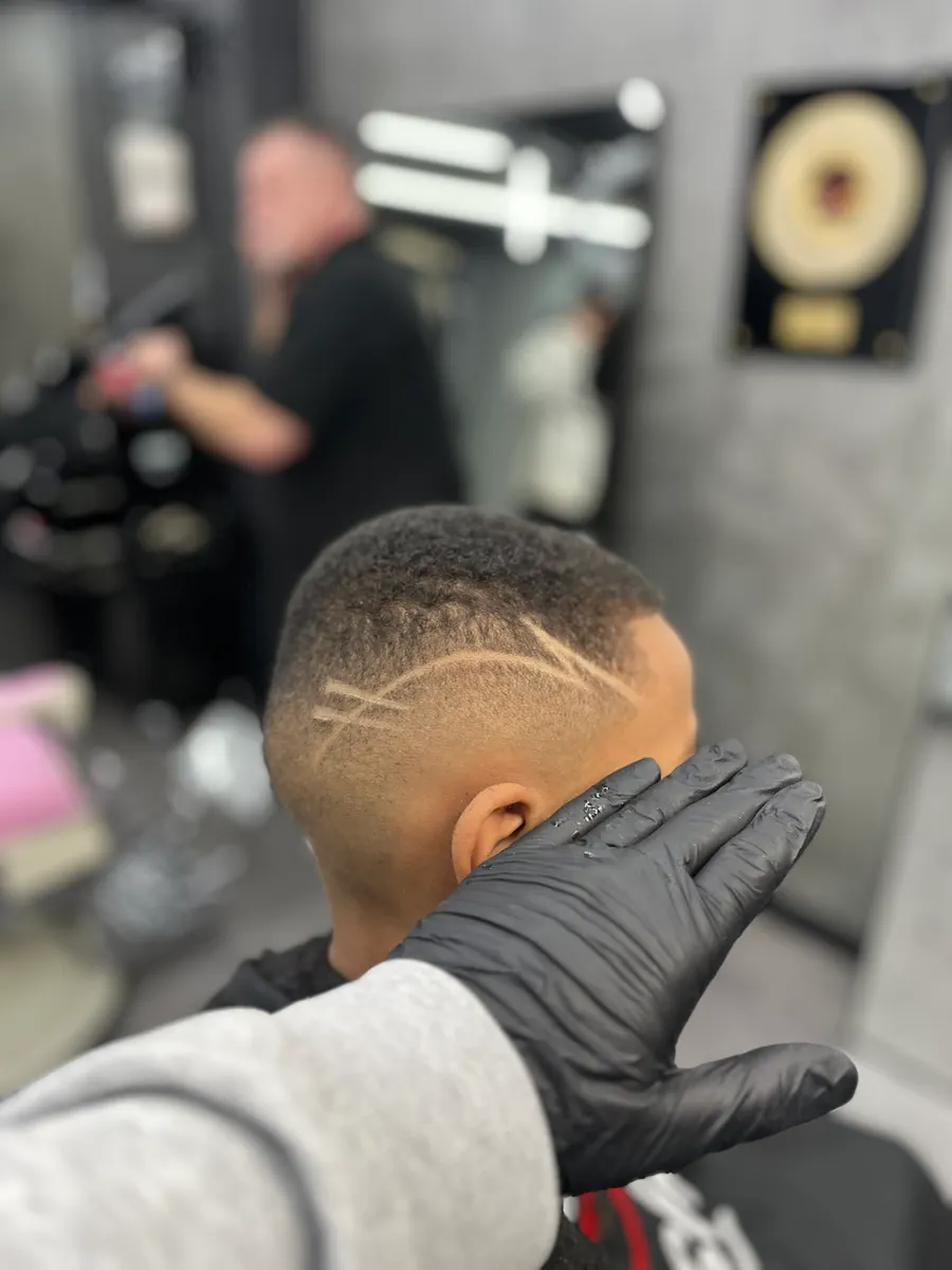 Kurzer Skin Fade mit eingeschnittenem Linienmuster, von hinten