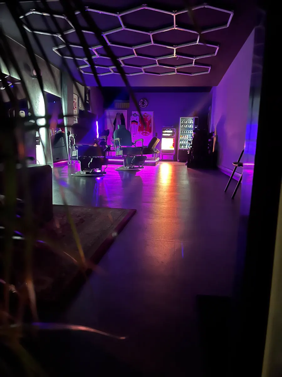 Blick in den Laden in Neonlicht, mit Getränkeautomat und Trikots an der Wand